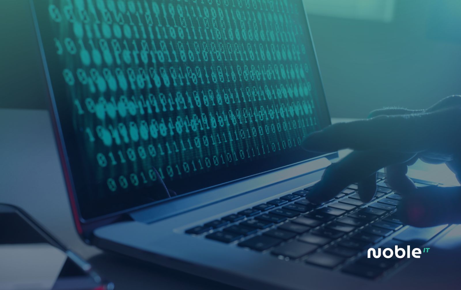 Hand typing on a laptop keyboard while the screen fills with binary code during a cyber attack